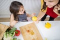 Little girl and her mother slicing vegetables on a cutting board Royalty Free Stock Photo