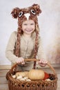 Happy little girl holding basket full of pumpkins