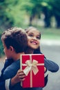 Happy little girl is holding gift in red box and smiling while hugging little boy Royalty Free Stock Photo