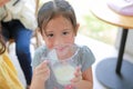 Happy little girl holding glass of fresh milk from the cows in dairy production farm