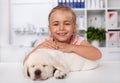 Happy little girl holding her sleeping puppy dog at the veterinary doctor office