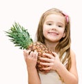 Happy little girl holding ripe whole pineapple