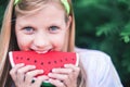 Happy little girl holding slice of watermelon at summer time.