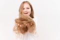 A happy little girl holds in hands cropped hair after cutting on a white