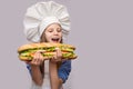 Happy little girl with hot dog and chef uniform isolated on white background Royalty Free Stock Photo