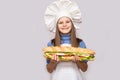 Happy little girl with hot dog and chef uniform on white background. Royalty Free Stock Photo