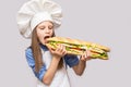 Happy little girl with hot dog and chef uniform on white background. Royalty Free Stock Photo