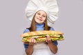 Happy little girl with hot dog and chef uniform on white background. Royalty Free Stock Photo