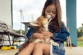 Happy little girl hug and kiss pretty corgi dog sitting outdoors on house yard. Child play with brown fluffy cute puppy. Royalty Free Stock Photo