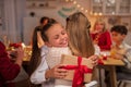 Happy little girl hugging her mother, receiving gift box during festive dinner at home Royalty Free Stock Photo