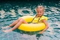 Happy little girl with inflatable rubber circle having fun in swimming pool