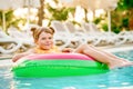 Happy little girl with inflatable toy ring float in swimming pool. Little preschool child learning to swim and dive in Royalty Free Stock Photo