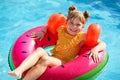 Happy little girl with inflatable toy ring float in swimming pool. Little preschool child learning to swim and dive in Royalty Free Stock Photo