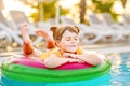 Happy little girl with inflatable toy ring float in swimming pool. Little preschool child learning to swim and dive in Royalty Free Stock Photo