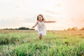 Happy little girl joyfully running across field. Carefree child on grassy meadow. Outdoor walking. Beautiful sunny sky. Royalty Free Stock Photo