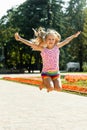 Happy little girl jumping in the park. little girl eating ice cream and having fun in the city Royalty Free Stock Photo