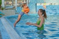 Happy little girl is jumping into the pool to her mother. The family swims in the pool on vacation. The daughter jumps Royalty Free Stock Photo