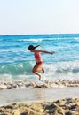 Happy Little Girl Jumping In Sea Waves. Jump Accompanied By Water Splashes. Summer Sunny Day, Ocean Coast Royalty Free Stock Photo