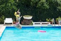 Happy little girl jumps in the pool; summertime background