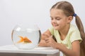 Happy little girl knocking his finger on the aquarium with goldfish Royalty Free Stock Photo