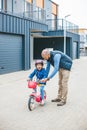 Happy girl laughing while her father teaching her to ride a bike Royalty Free Stock Photo