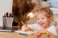 happy little girl laughing at her laptop and doing homework in a notebook home learning concept in the covid 19 Royalty Free Stock Photo