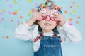 Happy little girl lies on a floor, holding onto her birthday glasses Royalty Free Stock Photo