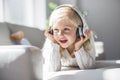 Happy little girl listening music lying on the sofa living-room Royalty Free Stock Photo