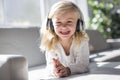 Happy little girl listening music lying on the sofa living-room Royalty Free Stock Photo