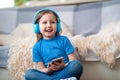 Happy little girl listening to music in blue headphones, at home Royalty Free Stock Photo