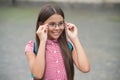 Happy little girl with long hair fix glasses on nose with cute look summer outdoors, eyewear