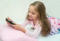 Happy little girl lying on bed with tablet computer Royalty Free Stock Photo