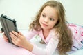 Happy little girl lying on bed with tablet computer Royalty Free Stock Photo