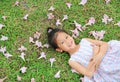 Happy little girl lying on green grass with fall pink flower in the garden outdoor Royalty Free Stock Photo