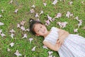 Happy little girl lying on green grass with fall pink flower in the garden outdoor Royalty Free Stock Photo