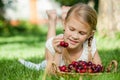 Happy little girl lying near the tree with a basket of cherries Royalty Free Stock Photo