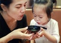 Happy little girl and mother blowing hot miso soup at japanese restaurant Royalty Free Stock Photo