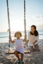 happy Little girl and mother swinging at the beach Royalty Free Stock Photo