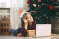 A happy little girl opens a gift under the Christmas tree at home and communicates with her grandparents via a laptop via video Royalty Free Stock Photo