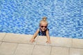 Happy little girl in outdoor swimming pool on hot summer day. Kids learn to swim. Children play in tropical resort. Family beach Royalty Free Stock Photo