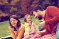 Happy little girl on picnic with her parents blowing dandelions Royalty Free Stock Photo