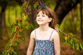 Happy little girl play near cherry tree in summer garden. Kid picking cherry on fruit farm. Child pick cherries in summer orchard.