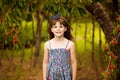 Happy little girl play near cherry tree in summer garden. Kid picking cherry on fruit farm. Child pick cherries in summer orchard.