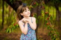 Happy little girl play near cherry tree in summer garden. Kid picking cherry on fruit farm. Child pick cherries in orchard.