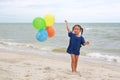 Happy little girl playing colorful balloons on the beach during summer vacation Royalty Free Stock Photo