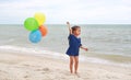 Happy little girl playing colorful balloons on the beach during summer vacation Royalty Free Stock Photo