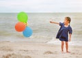 Happy little girl playing colorful balloons on the beach during summer vacation Royalty Free Stock Photo