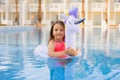 Happy little girl playing with colorful inflatable ring in outdoor swimming pool on hot summer day. Royalty Free Stock Photo