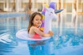 Happy little girl playing with colorful inflatable ring in outdoor swimming pool on hot summer day. Royalty Free Stock Photo