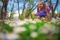 Happy little girl playing in the grass with flowers after the rain. She wear raincoat and yellow boots Royalty Free Stock Photo